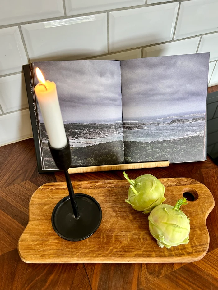 a candle on a cutting board next to a book