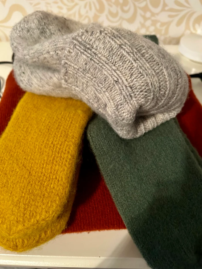 Three colorful knitted winter socks resting on a ledge.