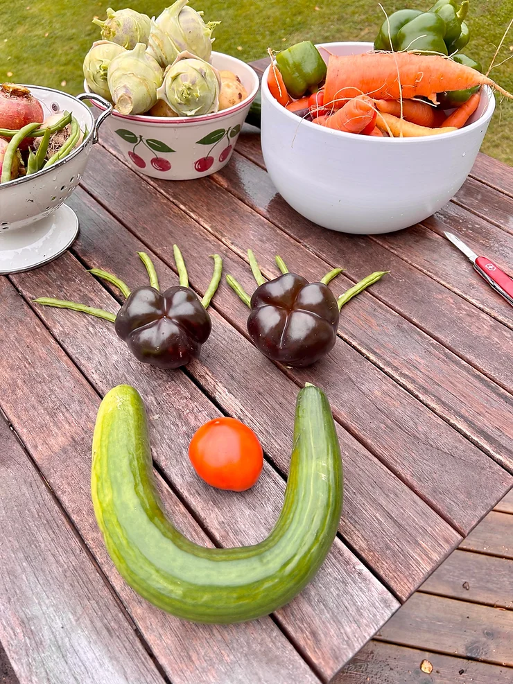 A creative display of vegetables arranged like a smiling face on a wooden table.