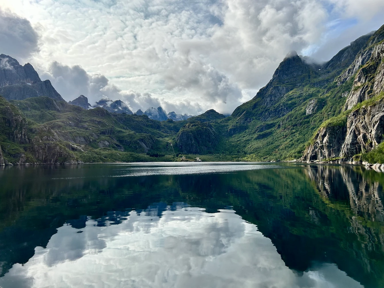 Majestic mountain landscape reflecting in a calm lake under a cloudy sky.